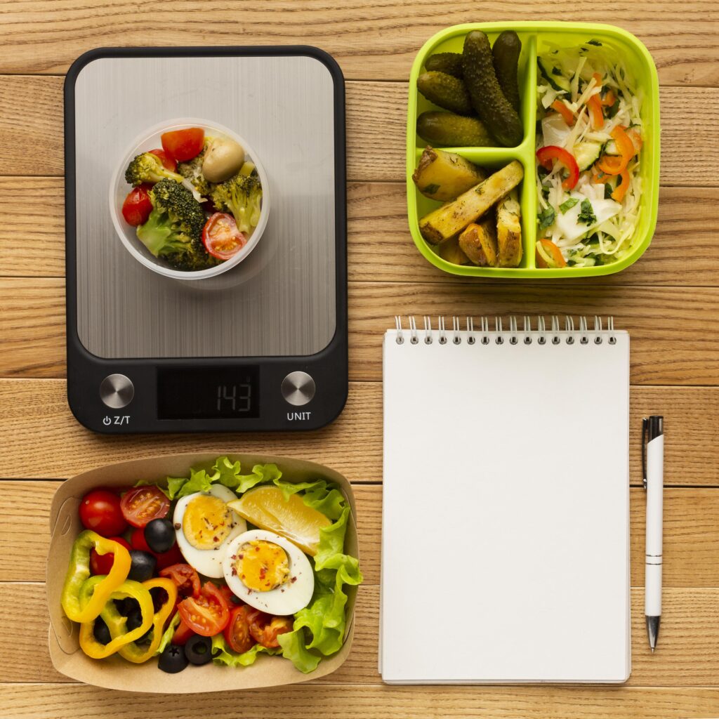 Why measuring your food intake is key to muscle growth and nutrition. A digital food scale measuring vegetables, alongside meal prep containers and a notebook for tracking nutrition and portion control